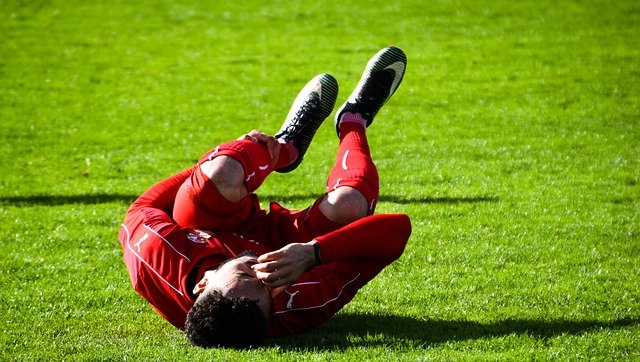 zraněný fotbalista ležící na trávníků